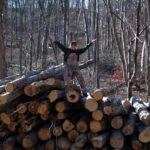 Bren on top of a pile of logs at Pioneer Mountain Homestead