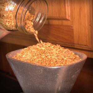 Grain poured into hopper of a grain mill.