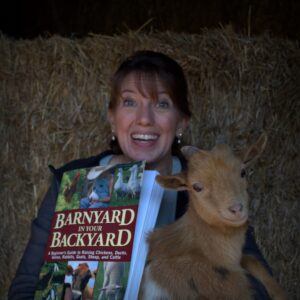 Bren holding the goat and displaying the book Barnyard in your Backyard