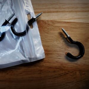 Screw hooks in a plastic bag with one out of the bag and to the right.