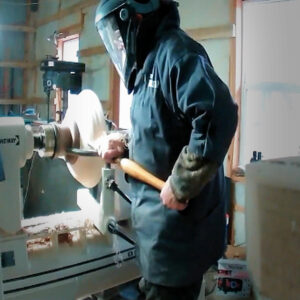 Chuck at lathe with face shield.