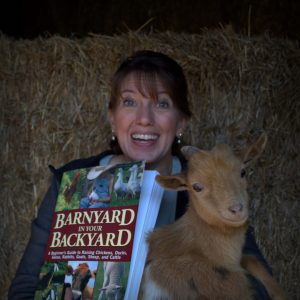 Bren holding the goat and displaying the book Barnyard in your Backyard